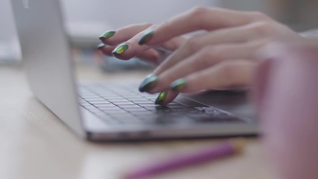 Close-up of young female Caucasian hands typing on laptop keyboard. Office work, modern technologies, online communication.