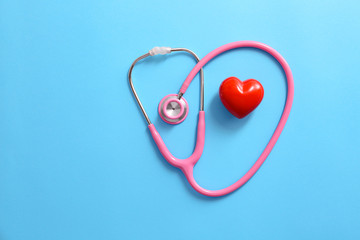 Stethoscope and red heart on color background. Cardiology concept
