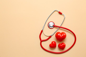 Stethoscope and red hearts on color background. Cardiology concept