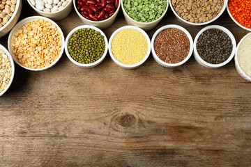Different grains and cereals on wooden table, flat lay. Space for text