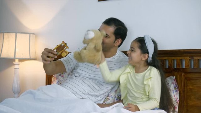 Indian father playing with daughter with her toys before going to sleep. . HD Stock Video of a beautiful relationship of an Indian man with his little daughter. Cute little girl laughing with her f...