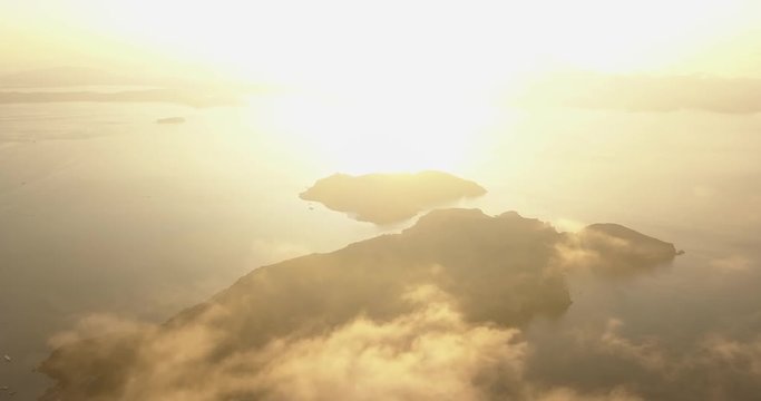 Aerial view, flying above the clouds, Sunrise and sunlight above Komodo Islands.