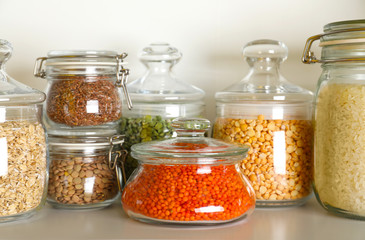 Different types of legumes and cereals in jars on table. Organic grains