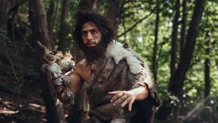 Portrait of Primeval Caveman Wearing Animal Skin and Fur Hunting with a Stone Tipped Spear in the...