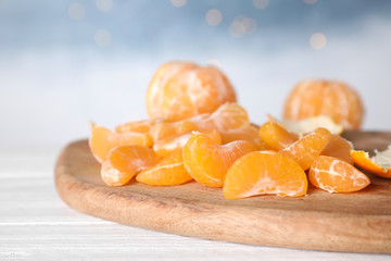 Segments of fresh juicy tangerines on white wooden table, closeup