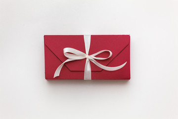 red gift box with white bow on a white background close-up