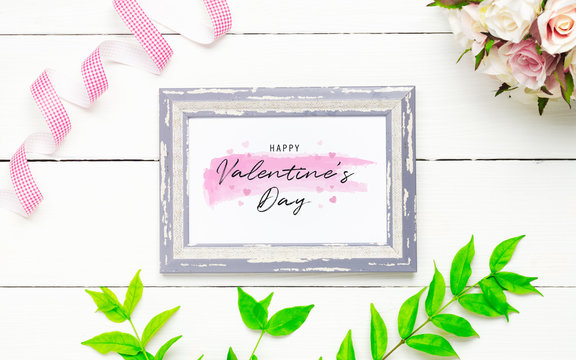 Mockup photo frame for Valentines day concept. Top view of mock up poto frame with rose flowers, green leaves and handy craft decorated on white wood background.