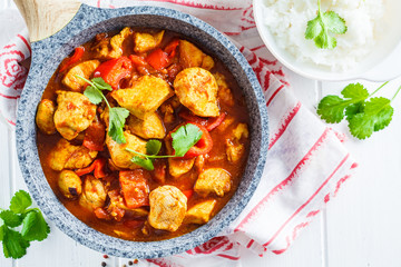 Jalfrezi chicken in fried pan with a bowl of rice, top view, copy space. Traditional indian cuisine concept.