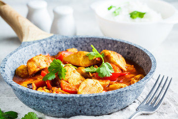 Jalfrezi chicken in fried pan with a bowl of rice, close up. Traditional indian cuisine concept.