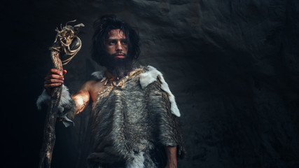 Primeval Caveman Wearing Animal Skin Holds Stone Hammer Stands Near Cave and Looks Around...