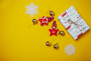 Naklejka premium Orange christmas card with toy red knitted christmas stars in funny hats and white gift boxes. Christmas flat lay on the orange background with copy space.