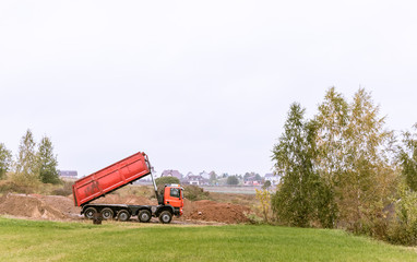 Fototapeta na wymiar A large 70-ton dump truck brought sand to a new construction site to add land