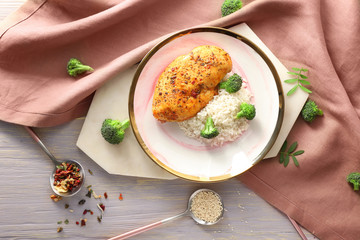 Plate with tasty rice and chicken on table