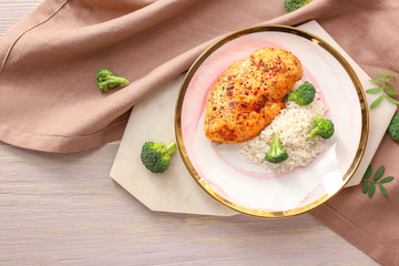 Plate with tasty rice and chicken on table