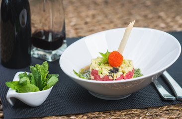 Classic traditional tartar salad laid in a round shape, stylish serving in an oriental style table in a restaurant. Tasty and healthy food. Guests service. Tar tar on a stylish plate with decor.