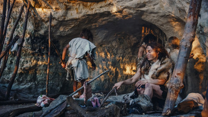 Tribe of Hunter-Gatherers Wearing Animal Skin Live in a Cave. Leader Brings Animal Prey from...