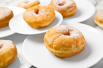 Plates with sweet tasty donuts on table