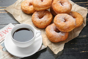 Sweet tasty donuts and cup of coffee on wooden background