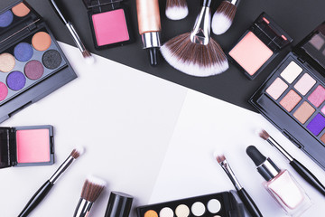 Creative beauty and makeup flat lay made with brushes, foundation, eye shadows and blush.