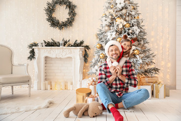 Happy father with little daughter in room decorated for Christmas