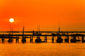 Fototapeta premium silhouette sunset at the sea. The way of life of fishermen on the bridge or jetty and returning from fishing from the sea. Chonburi, Thailand 22 Dec 2019.