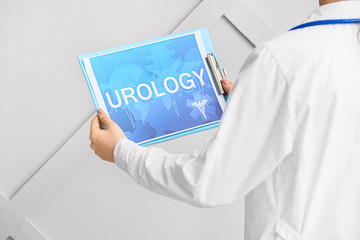 Doctor holding paper with text UROLOGY on light background