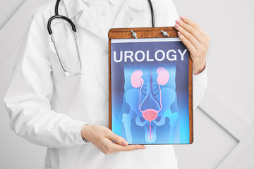 Doctor holding picture of urogenital system on light background
