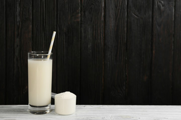 Protein shake and powder on white wooden table, space for text