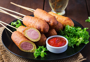 Traditional American corn dogs with mustard and ketchup on black plate. Street food. Copy space