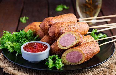 Traditional American corn dogs with mustard and ketchup on black plate. Street food. Copy space
