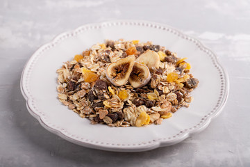 muesli with nuts and dry figs on dish on ceramic background
