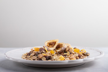 muesli with nuts and dry figs on dish on ceramic background