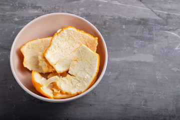 orange peel in small bowl on ceramic background