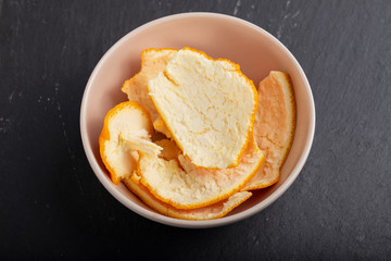 orange peel in small bowl on ceramic background