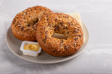 fresh bagels with butter and cheese on plate on ceramic background
