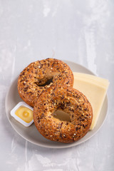 fresh bagels with butter and cheese on plate on ceramic background
