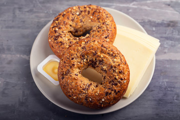 fresh bagels with butter and cheese on plate on ceramic background