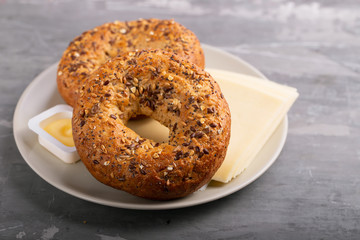fresh bagels with butter and cheese on plate on ceramic background