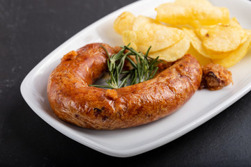 typical portuguese smoked sausage alheira with potato chips on white dish