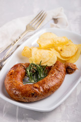 typical portuguese smoked sausage alheira with potato chips on white dish