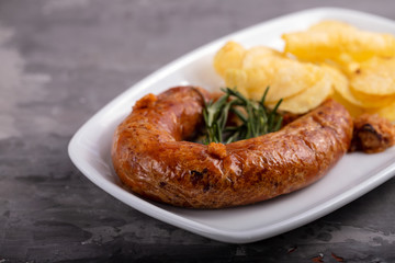 typical portuguese smoked sausage alheira with potato chips on white dish