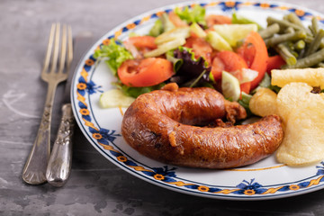 typical portuguese smoked sausage alheira with potato chips on white dish