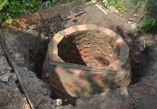 Installing brick septic tank. Sewer brick tank hole installation on house construction site