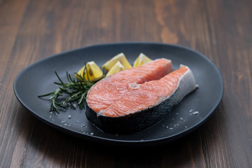 raw salmon with rosemary and lemon on dark plate