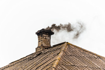 Black smoke from the chimney of an apartment building during heating and heating on the roof of...