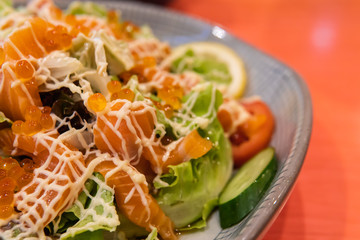Salad salmon topped with salmon roe serving with vegetable.