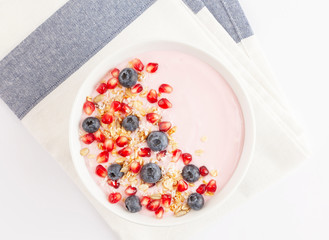 Breakfast smoothie bowl with yogurt, granola, blueberries, pomegranate seeds and shredded coconut. Healthy breakfast. Top view. 