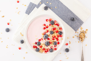 Breakfast smoothie bowl with yogurt, granola, blueberries, pomegranate seeds and shredded coconut. Healthy breakfast. Top view. 