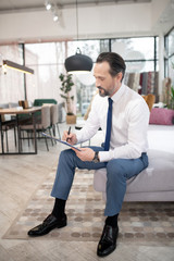 Furniture designer in tie and white shirt making drawings