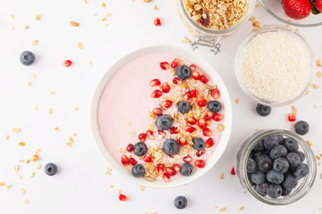 Obraz na płótnie Canvas Breakfast smoothie bowl with yogurt, granola, blueberries, pomegranate seeds and shredded coconut. Healthy breakfast. Top view. 